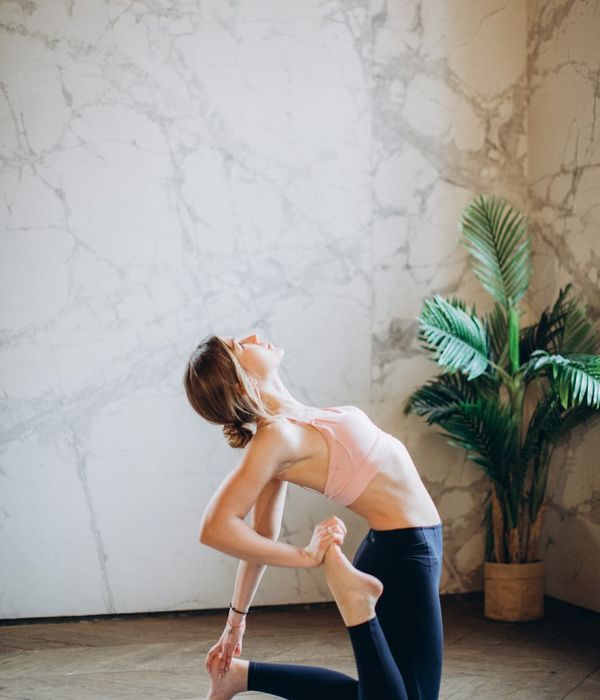 Woman in a calming back-stretching yoga pose in a bright studio.